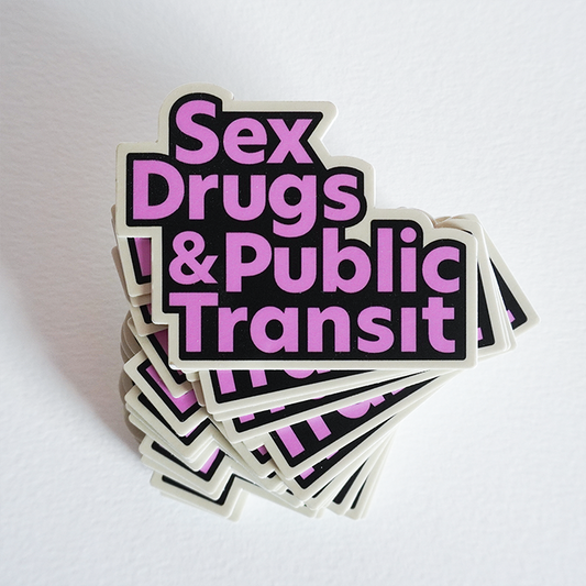 A pile of vinyl stickers with the same design. The design  has the words "Sex Drugs and Public Transit" in a pink, black, and cream motif.